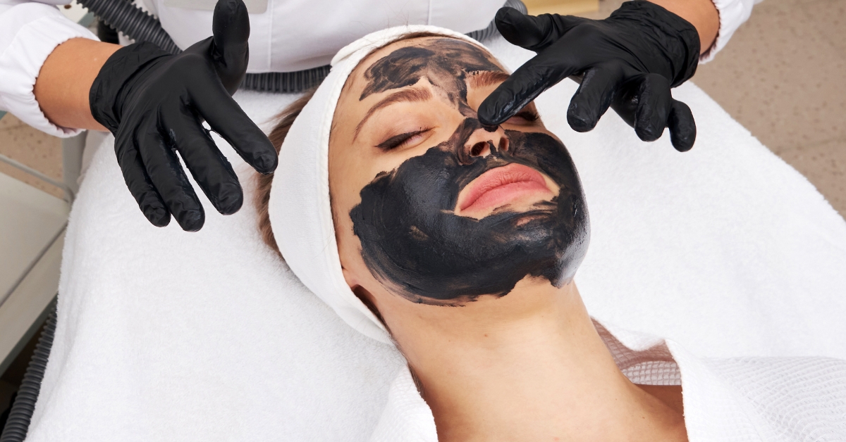 woman getting facial peel with black mask